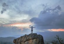 5 Ways to Stand Out Amongst your Peers A man posing on a mountain top as the sun sets