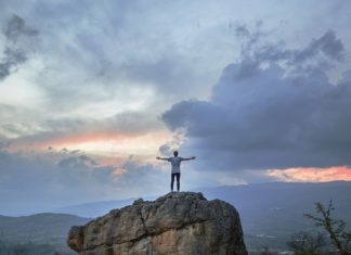 5 Ways to Stand Out Amongst your Peers A man posing on a mountain top as the sun sets