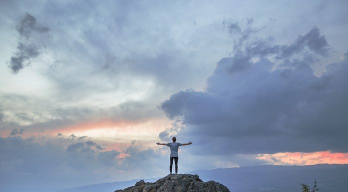 5 Ways to Stand Out Amongst your Peers A man posing on a mountain top as the sun sets